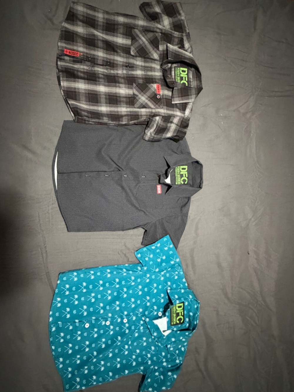 Three DIXXON youth XS Button-Up Shirts – Black Plaid, Charcoal, Teal Palm Print